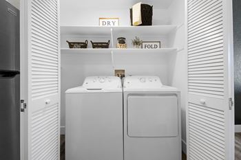 a washer and dryer in a white laundry room with white closet doors